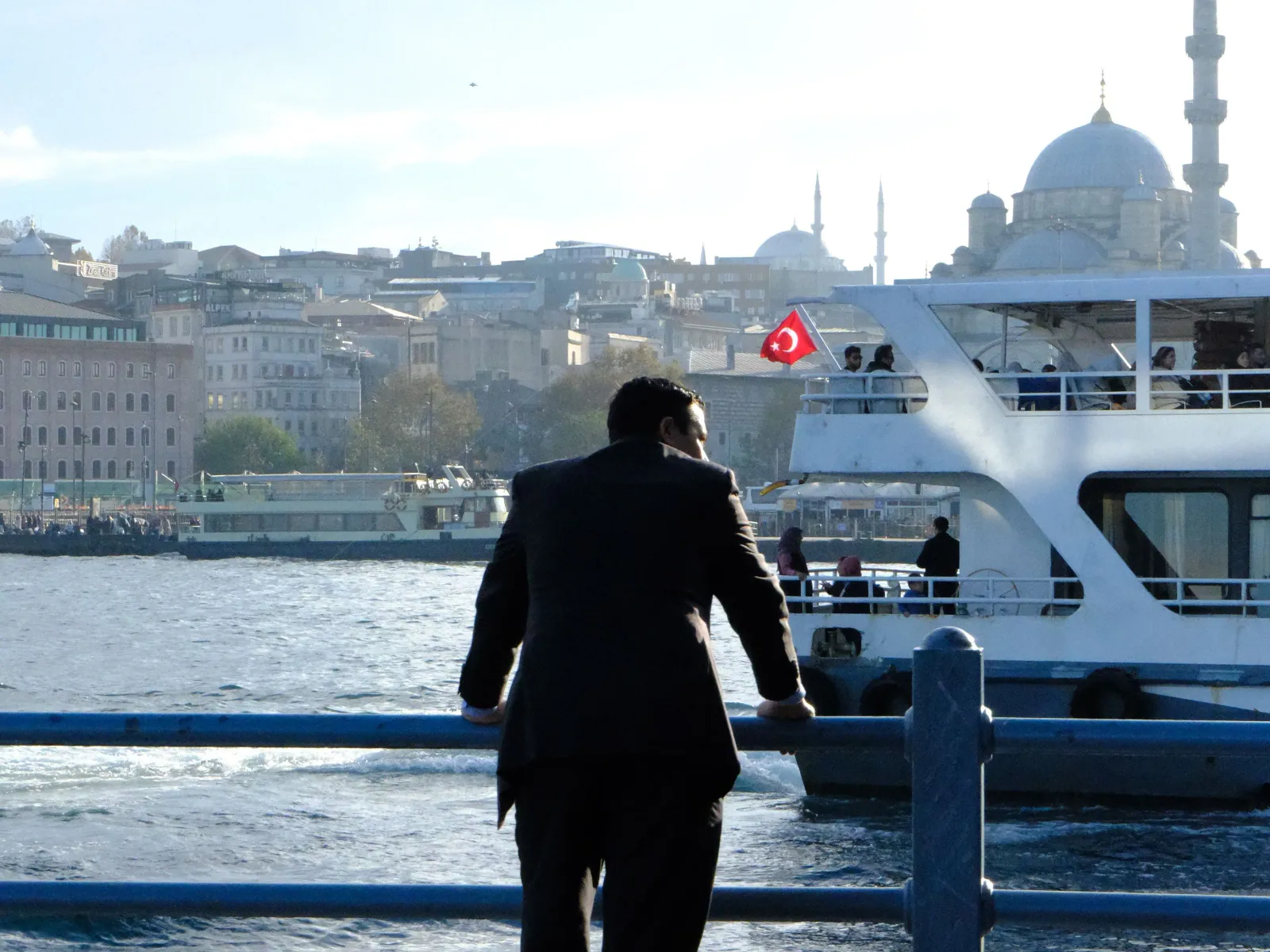 İstanbul Boğazı kıyısında vapur ve Türk bayrağı önünde duran iş insanı